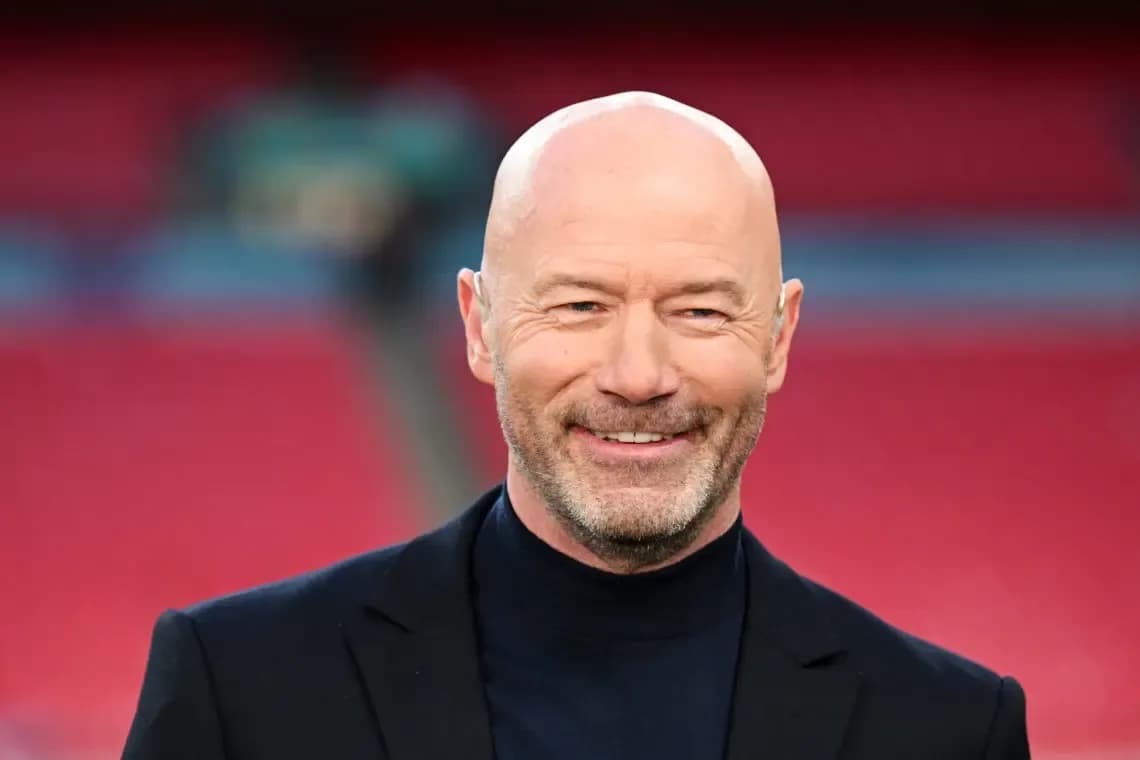Bald man in a black suit smiling at stadium