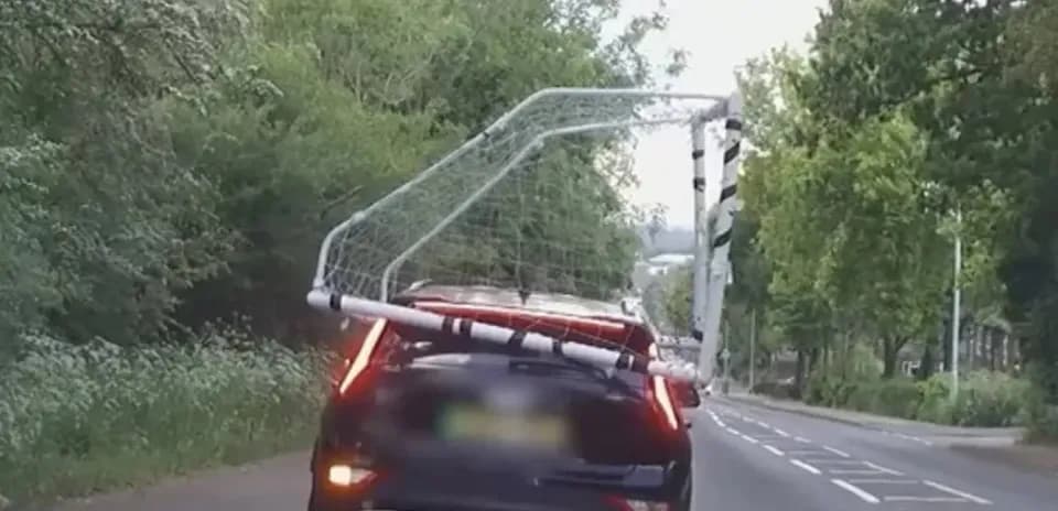 Car transporting a football goal on the road