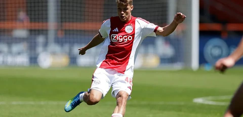 Player in Ajax kit kicking the ball during match