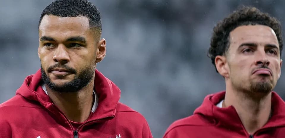 Two Liverpool players in training jackets during warm-up