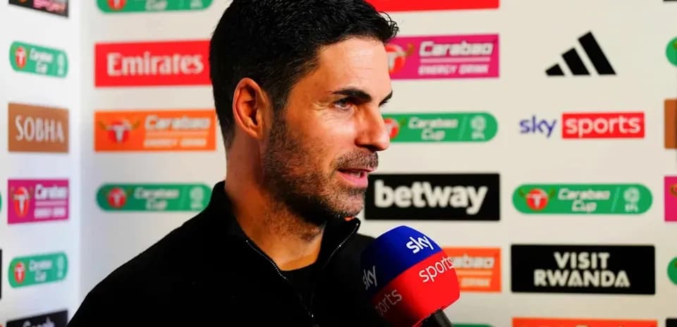 Manager speaking during press conference with sponsors' logos
