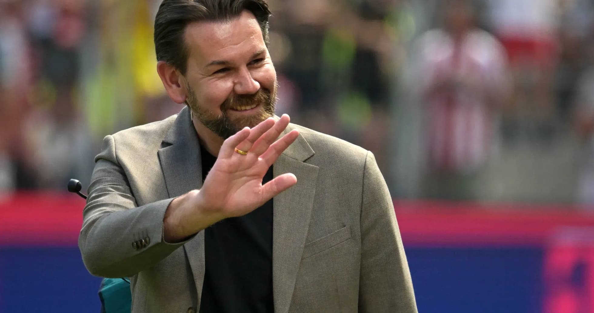 Man waving during a sports event on field
