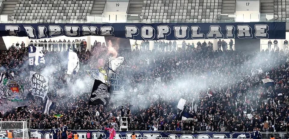 Crowd cheering with banners and smoke in stadium