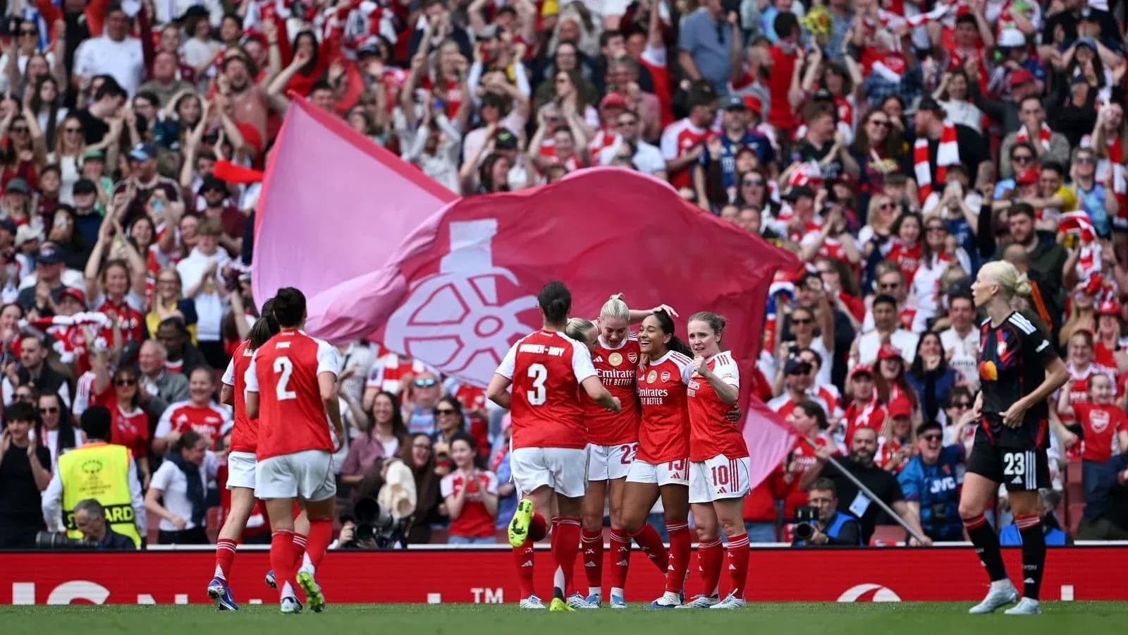 Arsenal women celebrating a goal with fans in background