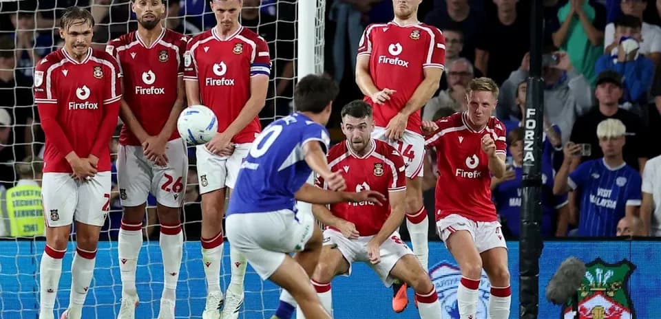 Player taking a free kick against defensive wall