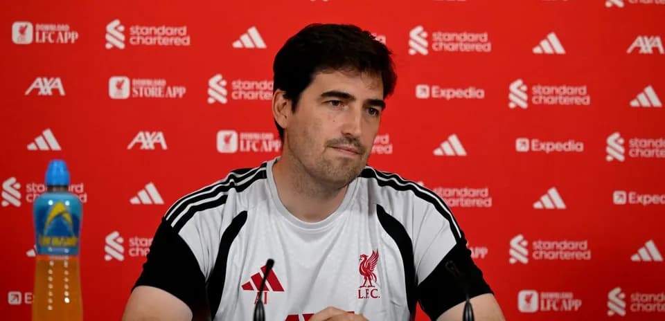 Man at press conference with Liverpool branding backdrop