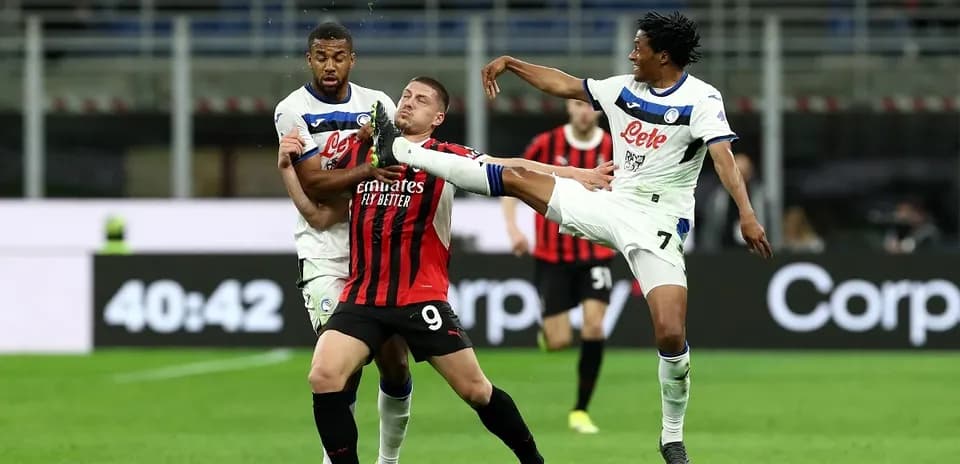 AC Milan player challenged by Atalanta defenders