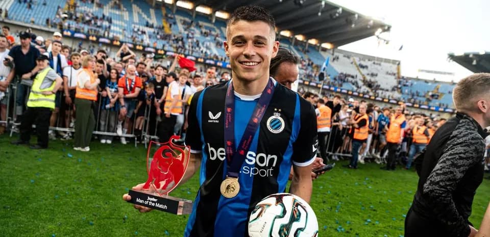 Player holding trophy and ball on pitch celebration