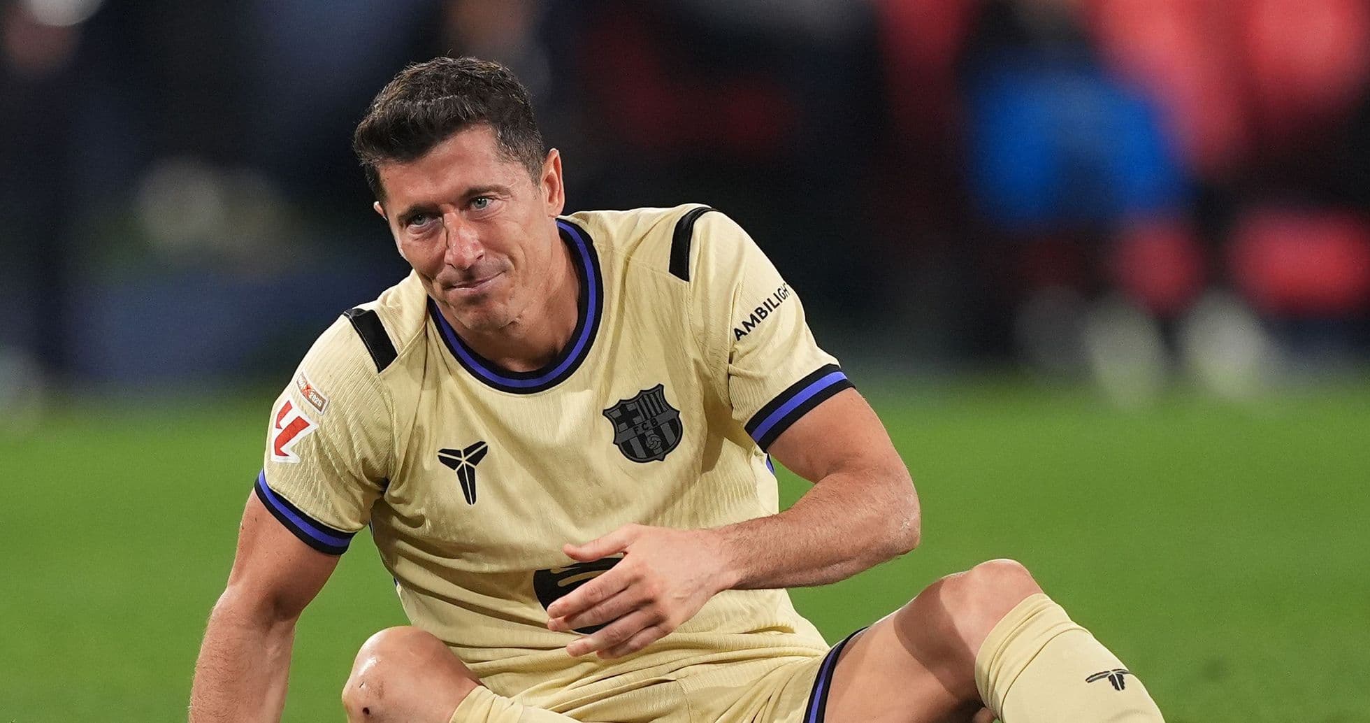 Player sitting on field wearing FC Barcelona kit