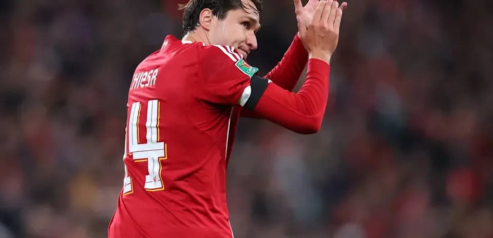 Player in red jersey applauding fans during match
