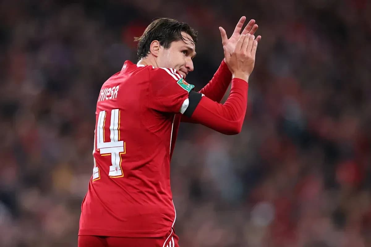 Player in red jersey applauding fans during match