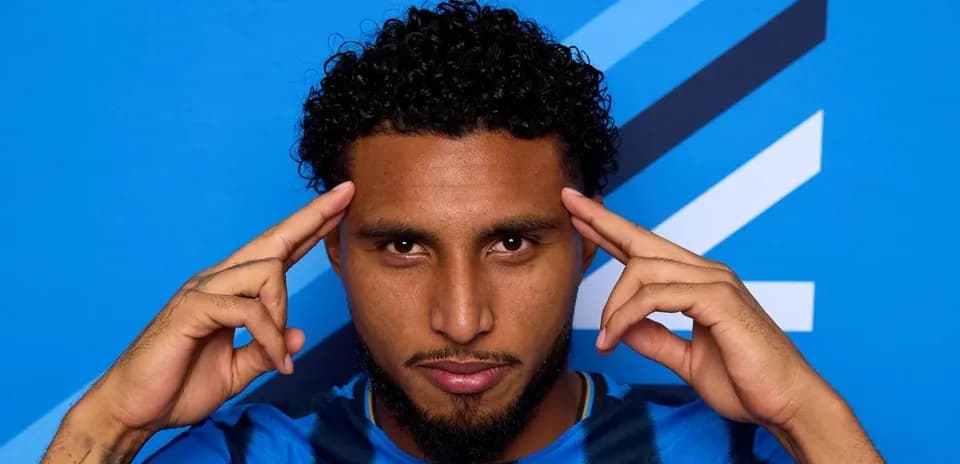 Player posing with hands on temples against blue background