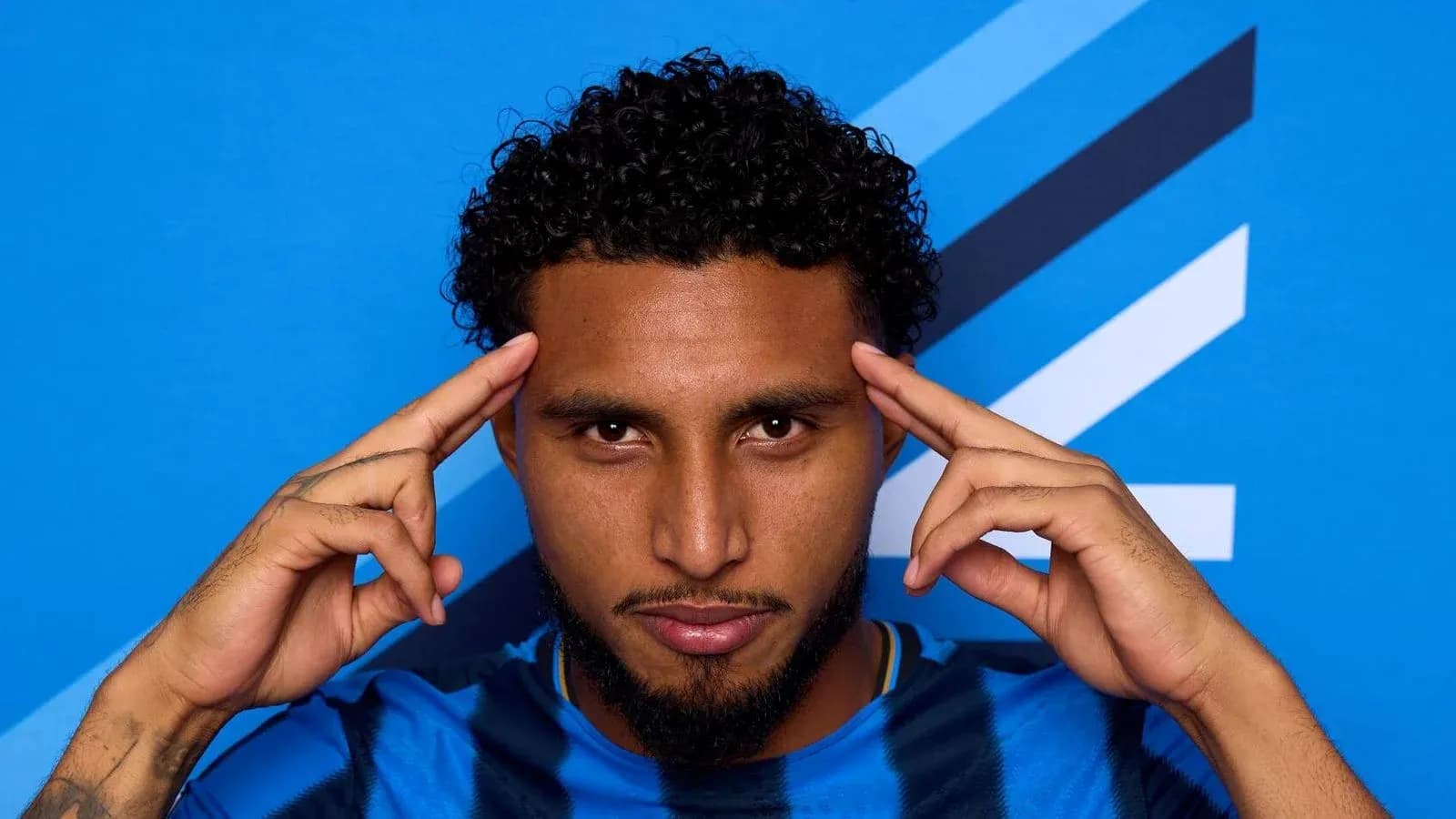 Player posing with hands on temples against blue background