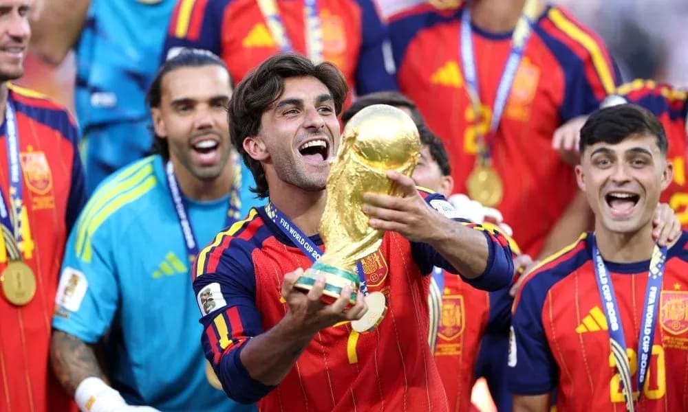 Player celebrating with FIFA World Cup trophy surrounded by teammates