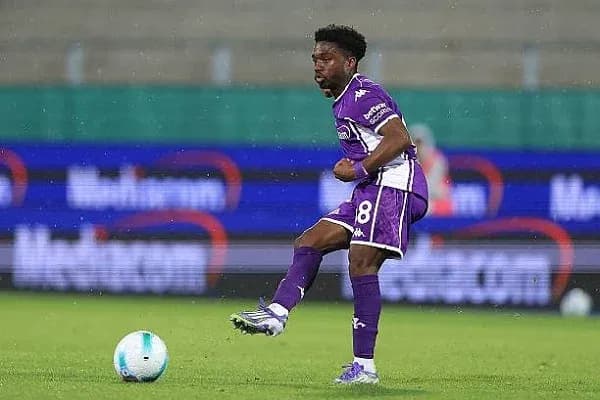 Player in purple kit controlling soccer ball on field