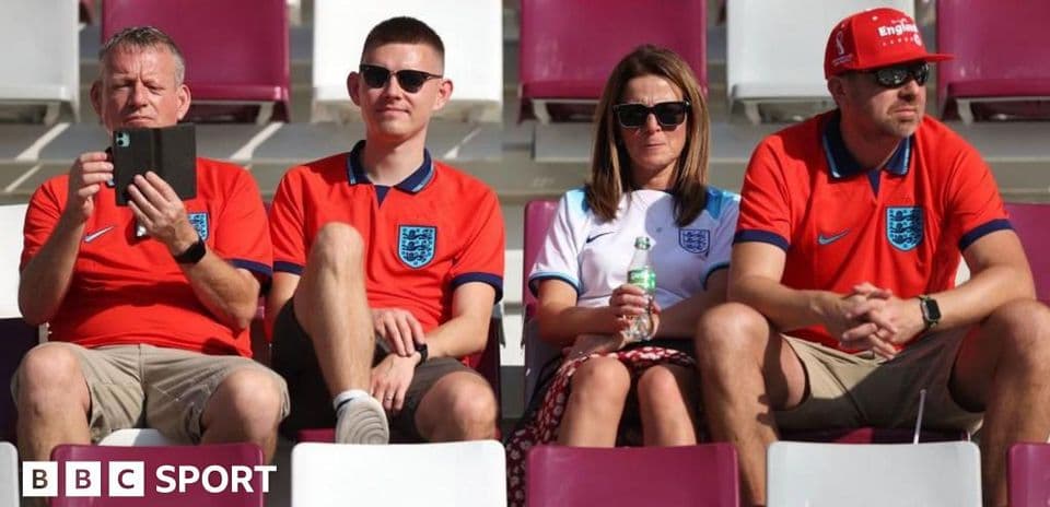 Four England fans sitting in stadium stands