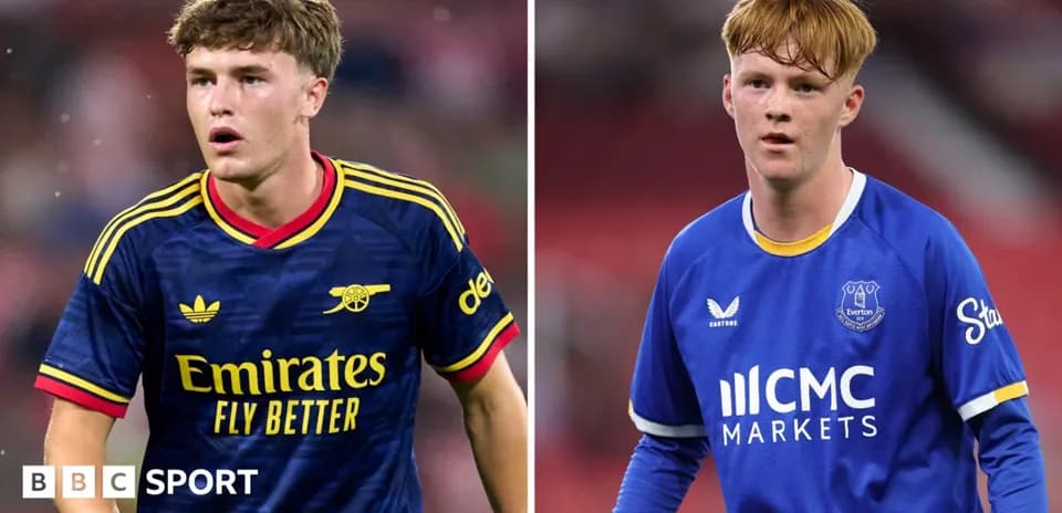 Two young footballers in team kits on the field