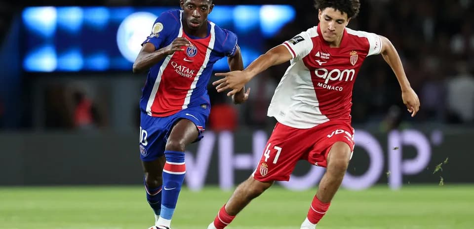 Player in blue and red jersey dribbling past opponent