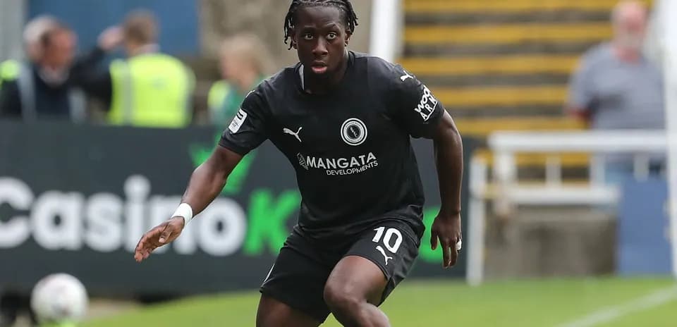 Player in black kit dribbling the ball on field