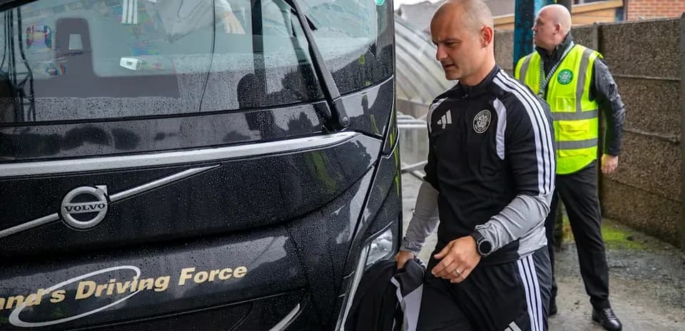 Coach and staff arriving at team bus in rain