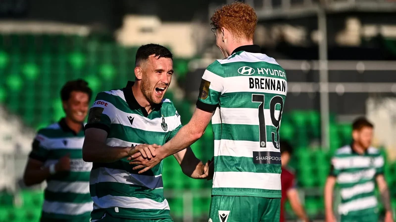 Players celebrating a goal in green and white jerseys