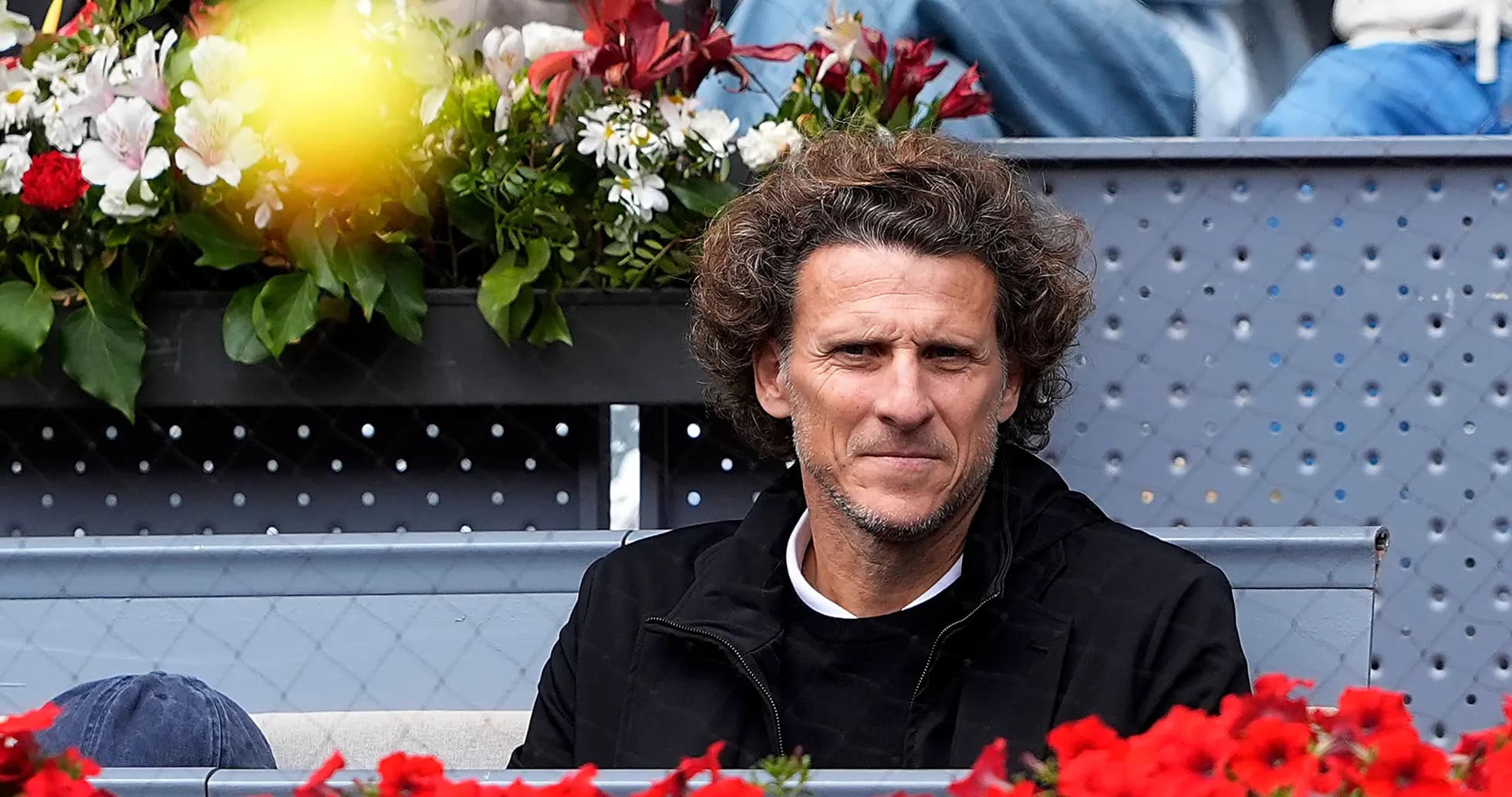 Man seated among flowers at a tennis event