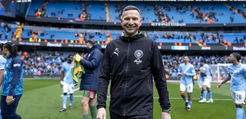 Coach smiling while walking off the pitch