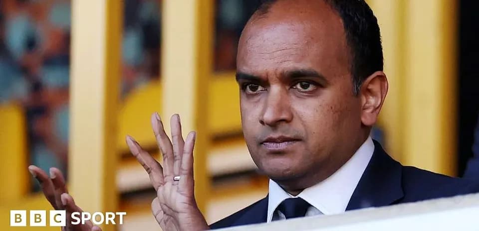 Person gesturing from VIP box at sporting event