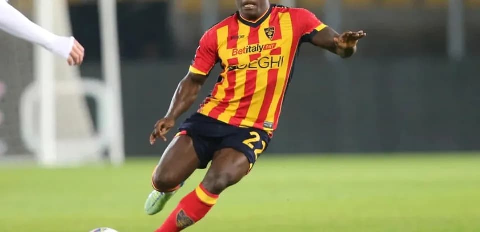 Player in red and yellow jersey dribbling ball on field