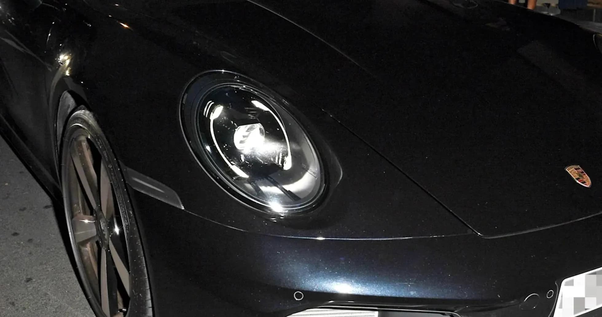 Two men inside a black Porsche sports car