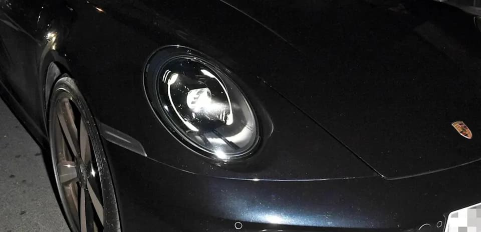 Two men inside a black Porsche sports car