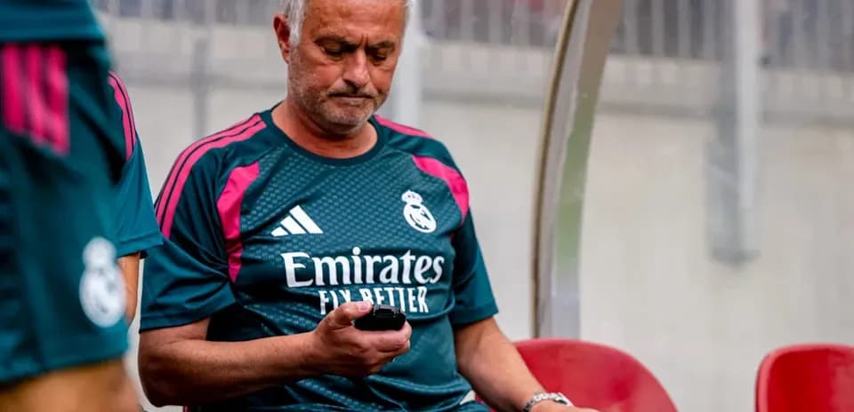 Manager sitting on bench, checking phone during match