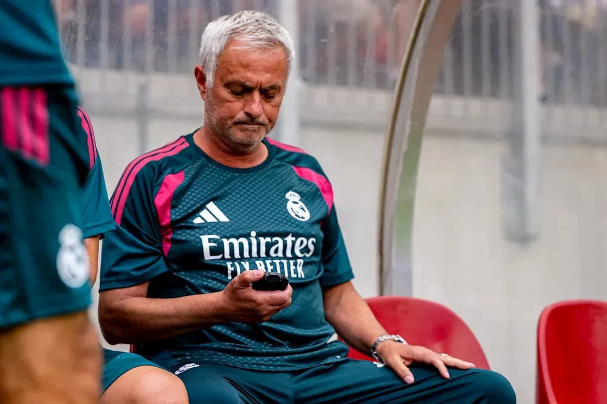 Manager sitting on bench, checking phone during match