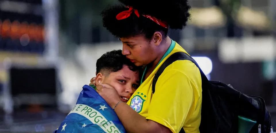 Two fans embracing, wrapped in Brazilian flag