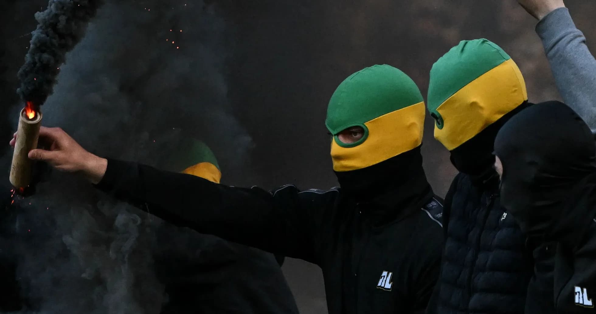 Masked individuals holding a flare in smoke