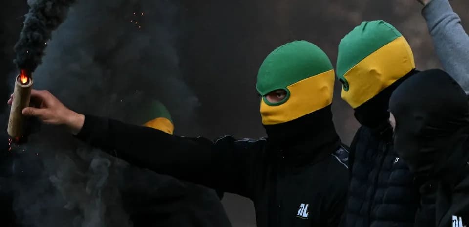 Masked individuals holding a flare in smoke