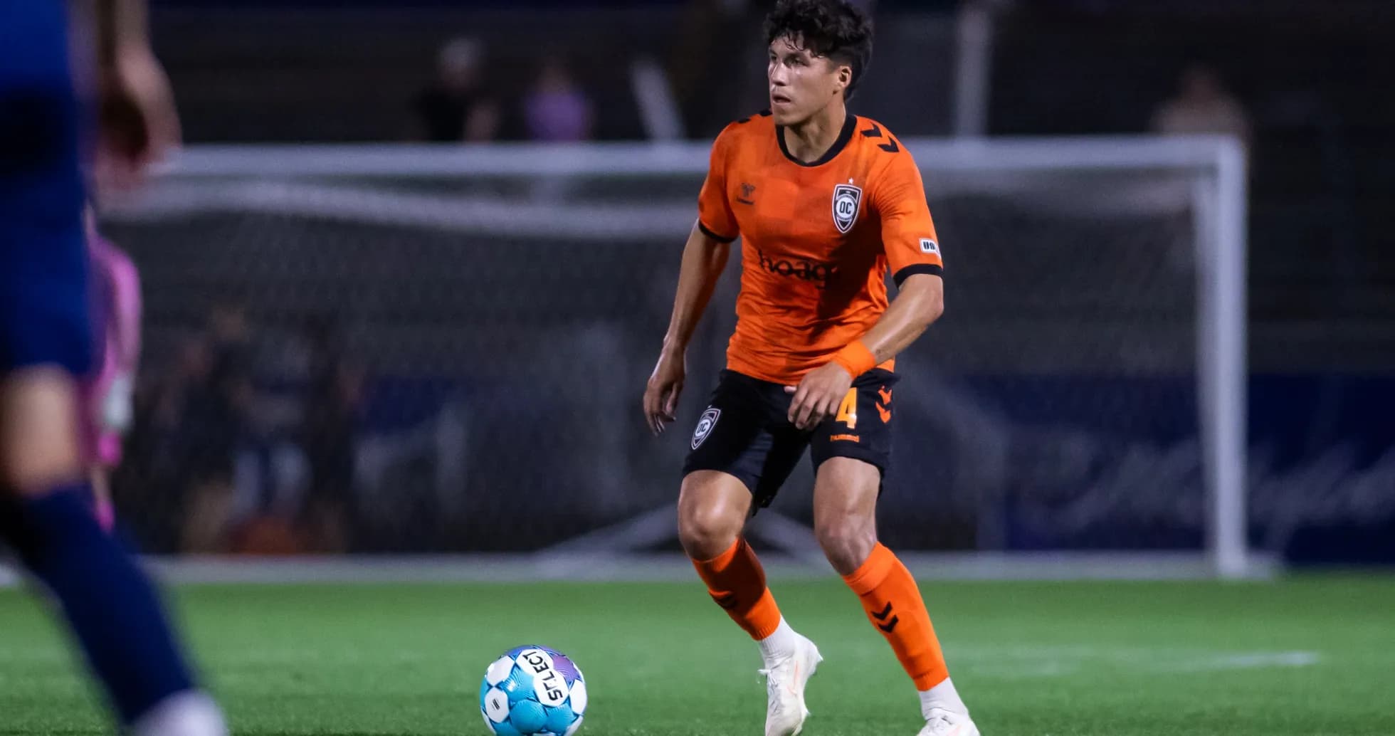 Player in orange jersey with soccer ball