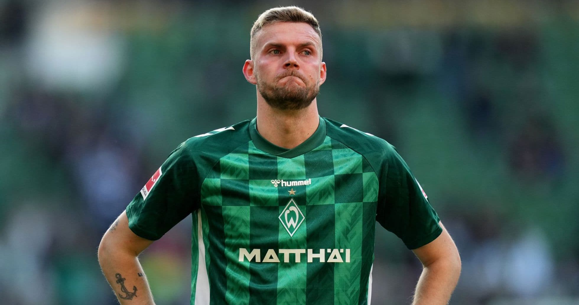 Player in green kit during match, looking concerned