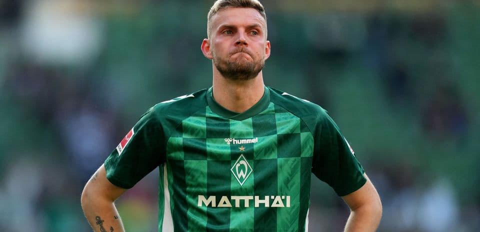 Player in green kit during match, looking concerned