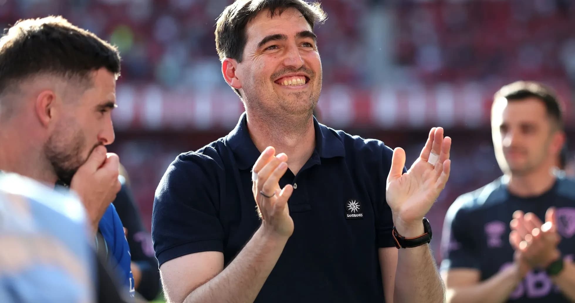 Coach applauding with players in background