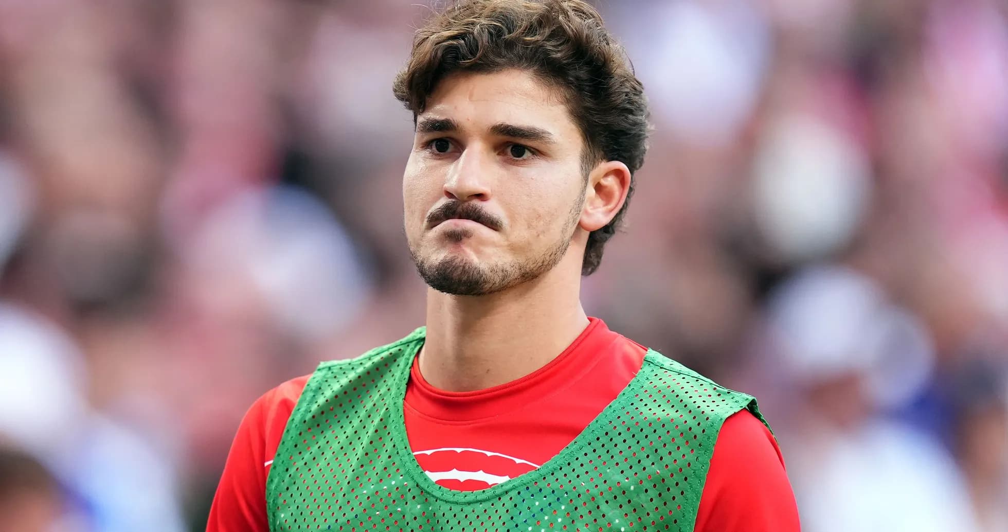 Player in green training vest on sidelines