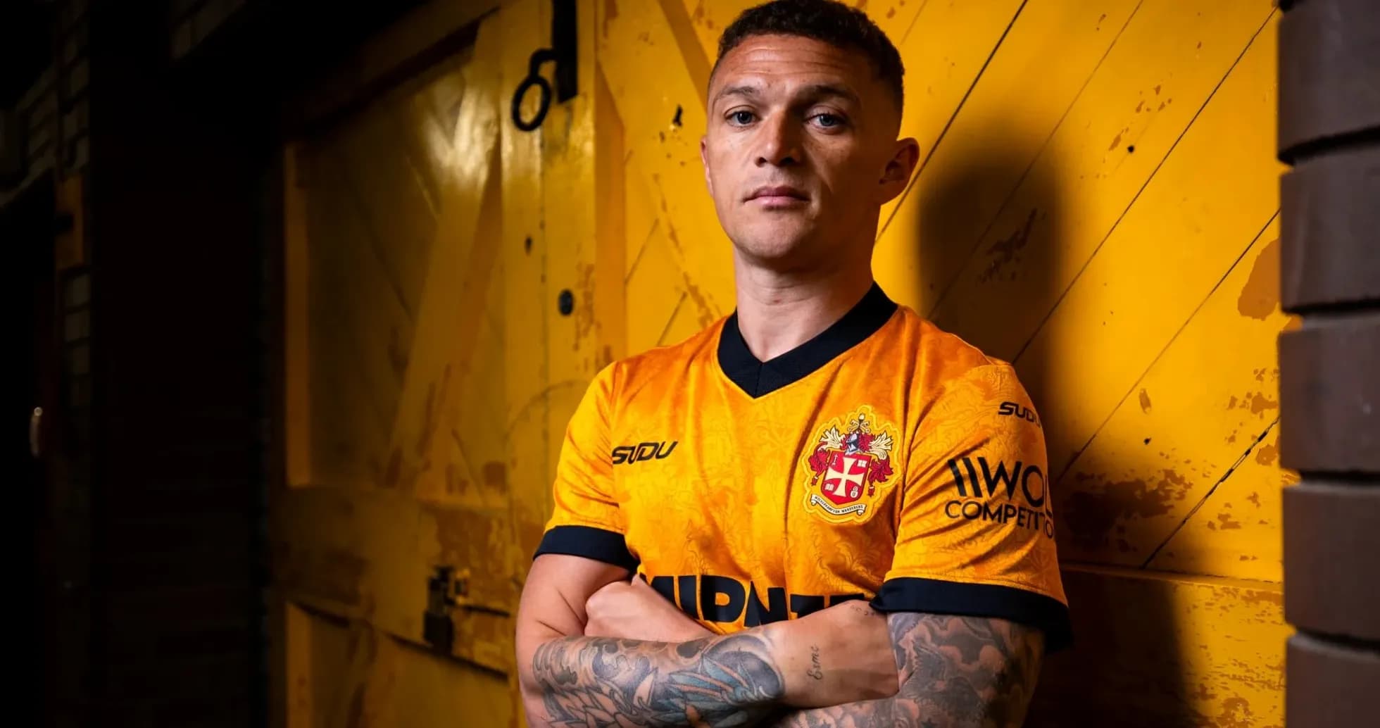 Player posing in orange team jersey against yellow backdrop