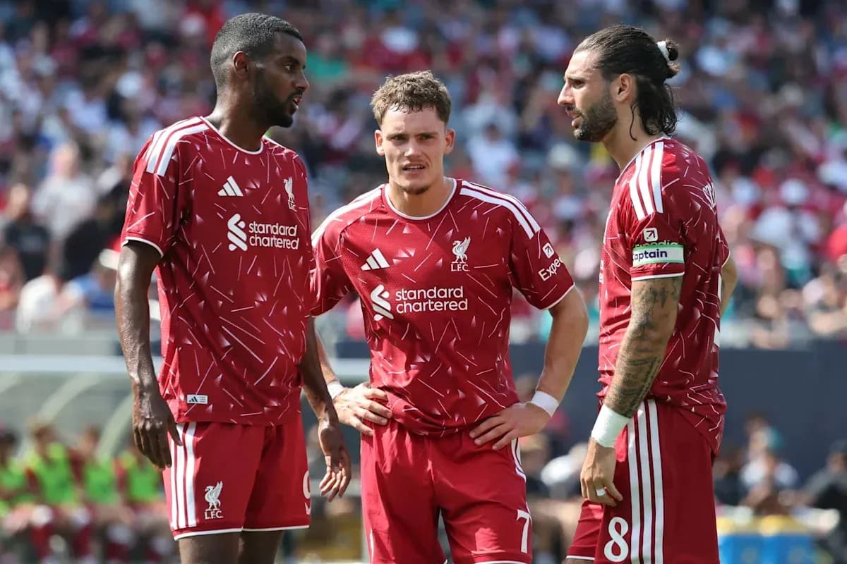 Three Liverpool players discussing on the pitch Three Liverpool players discussing on the pitch