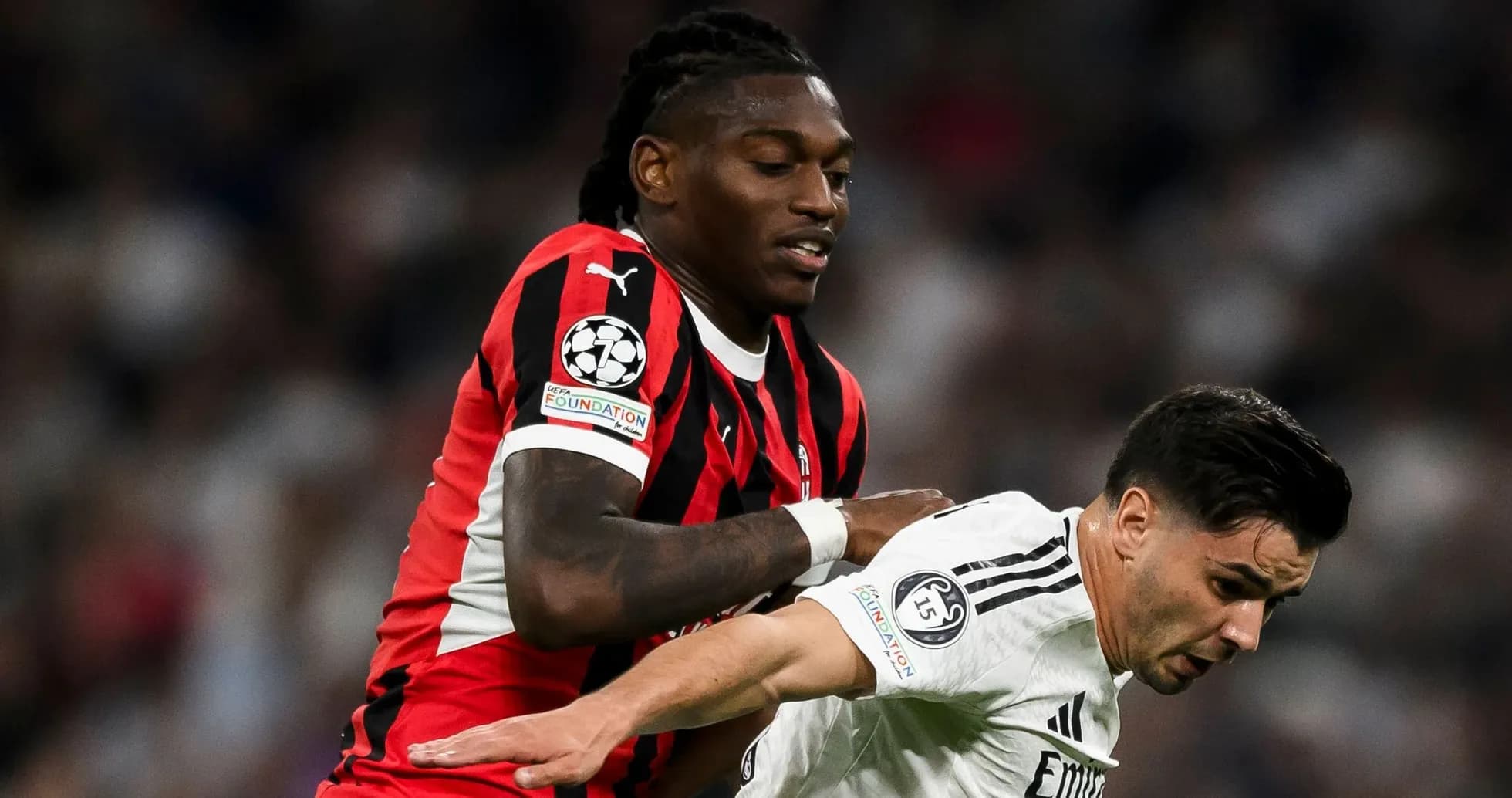 Player in red and black jersey tackling opponent Player in red and black jersey tackling opponent