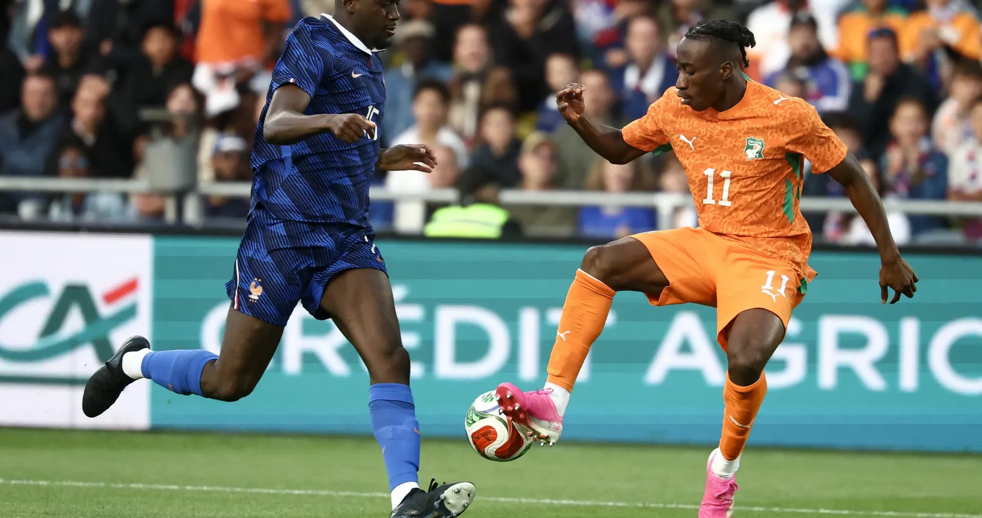 Player in orange dribbling past defender in blue Player in orange dribbling past defender in blue