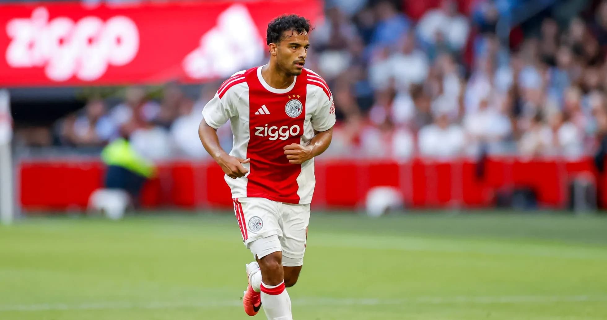 Player in Ajax kit running with ball during match Player in Ajax kit running with ball during match
