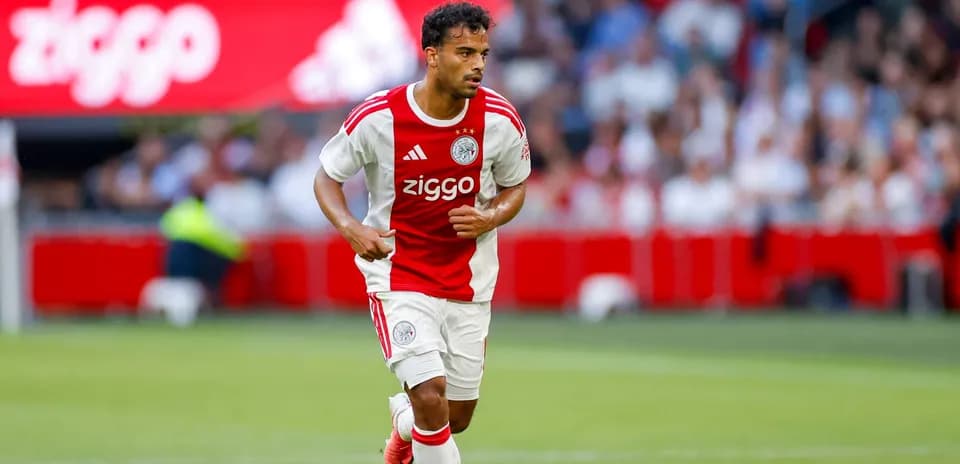 Player in Ajax kit running with ball during match Player in Ajax kit running with ball during match