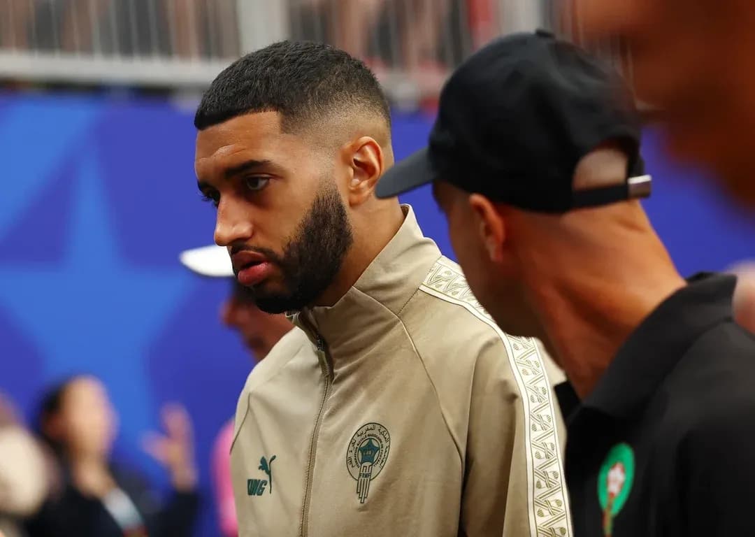 Player in team jacket talking with another person Player in team jacket talking with another person