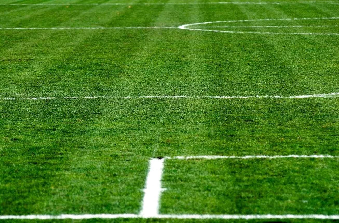 Green football pitch with white boundary lines Green football pitch with white boundary lines