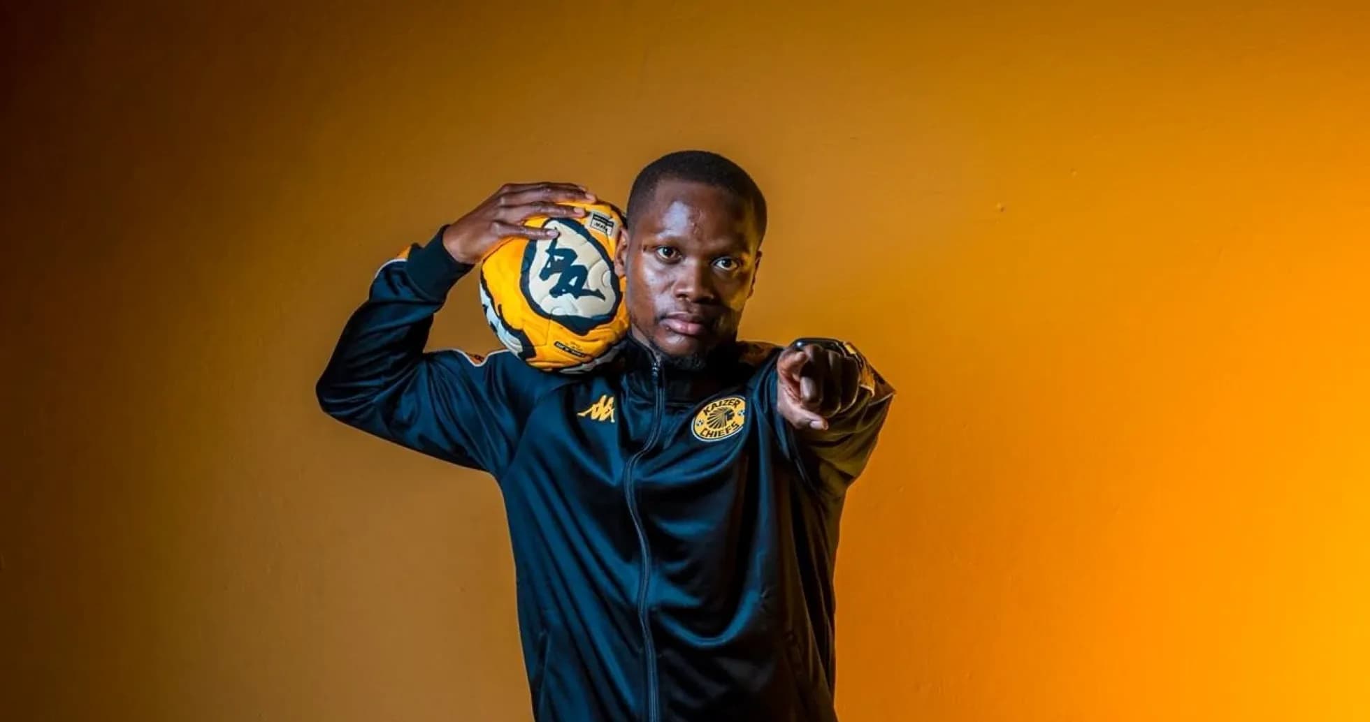 Player posing with soccer ball against orange background Player posing with soccer ball against orange background